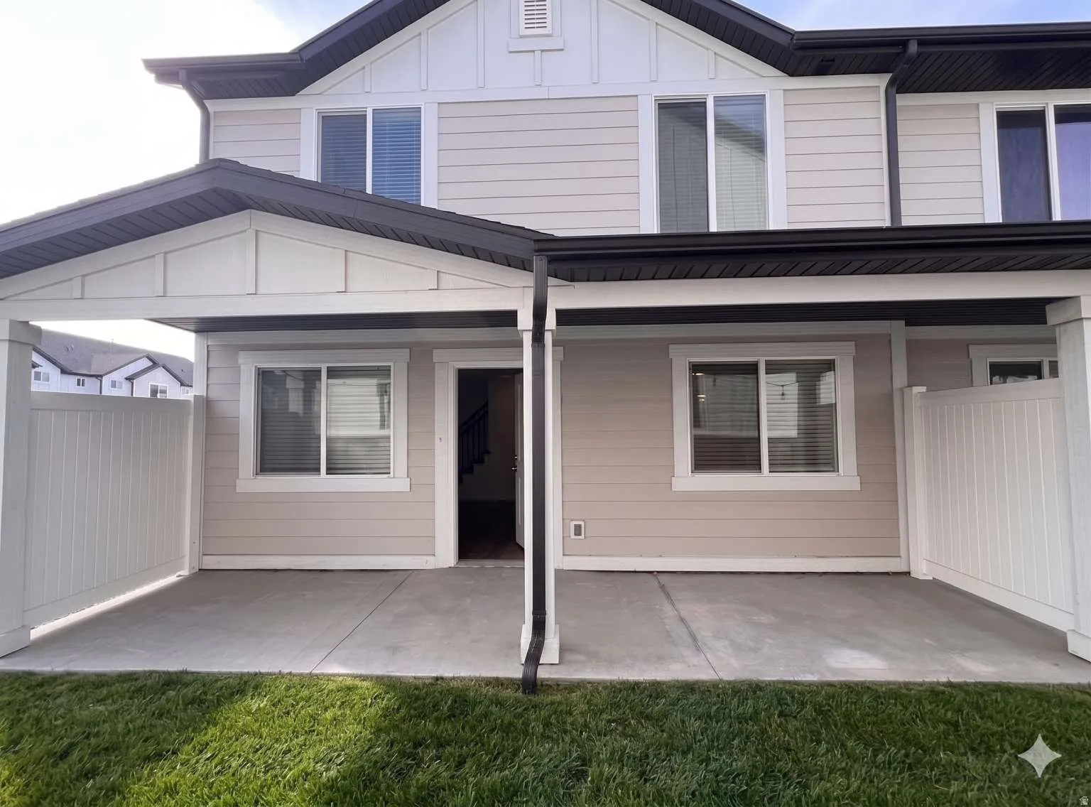 Covered concrete patio space featuring a partial privacy fence