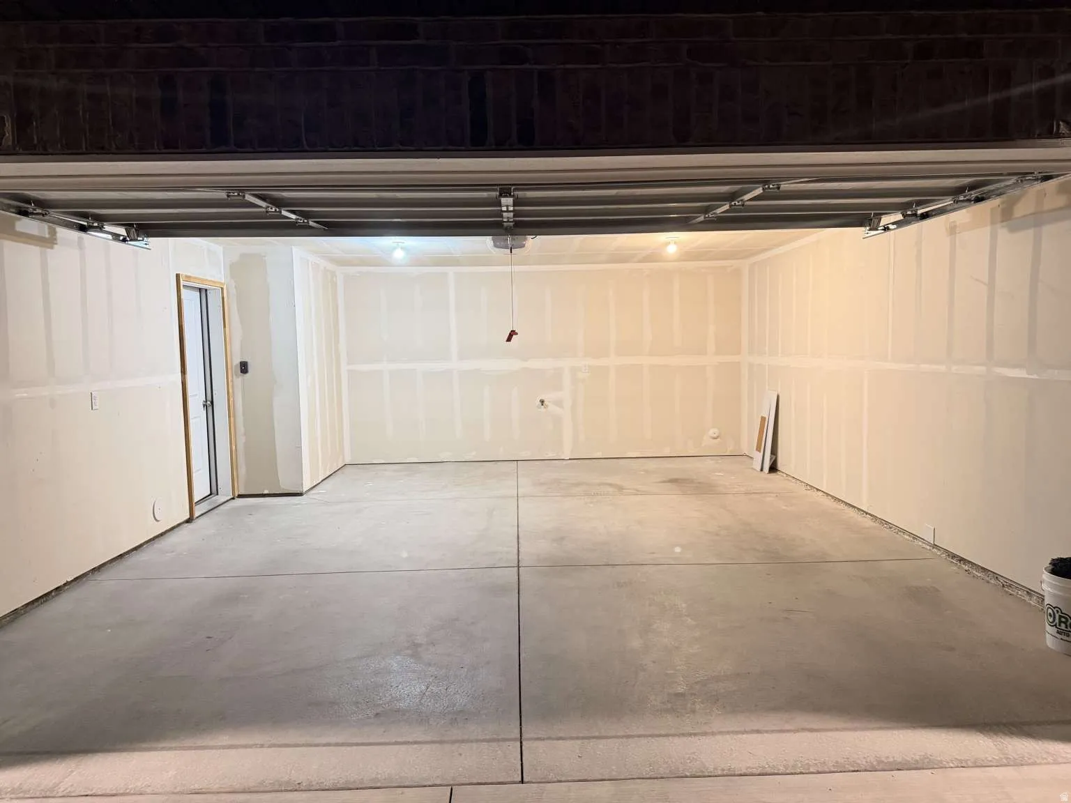 Spacious garage featuring a concrete floor, sheetrock walls, and an interior access door