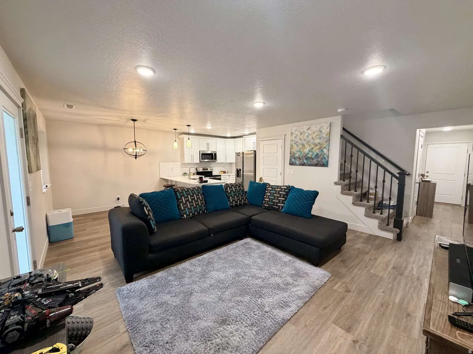 Open-concept living space featuring wood-finish flooring, recessed lighting, and a modern light fixture