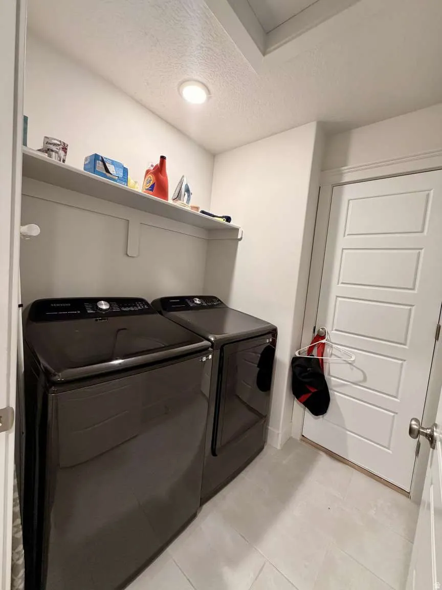 Dedicated laundry area featuring a built-in shelf, recessed lighting, and light-toned tile flooring