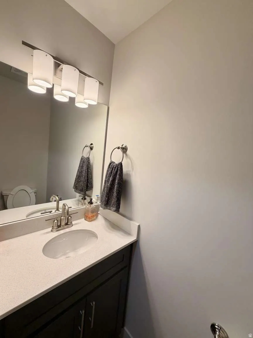 Bathroom vanity with a light-colored countertop, integrated sink, and brushed nickel faucet