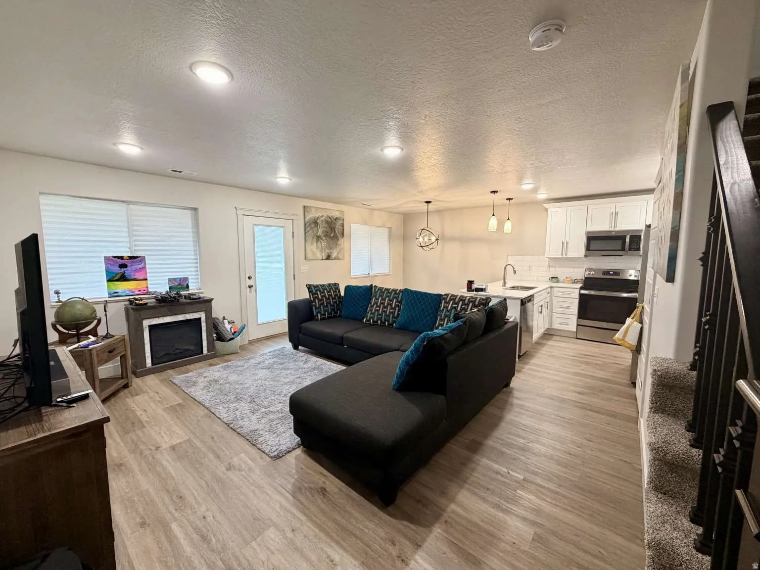 Open-concept living space featuring wood-finish flooring, recessed lighting, and a built-in fireplace with a mantel
