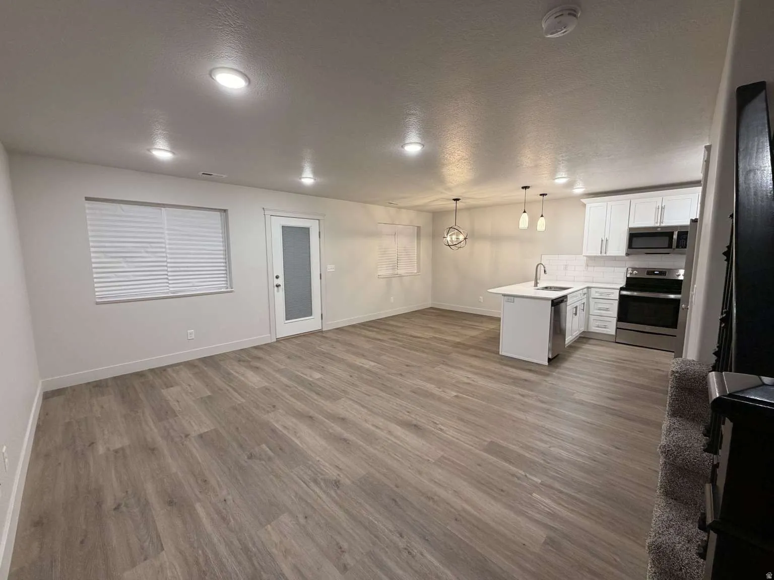 Open-concept living area featuring wood-finish flooring, recessed lighting, and a modern kitchen