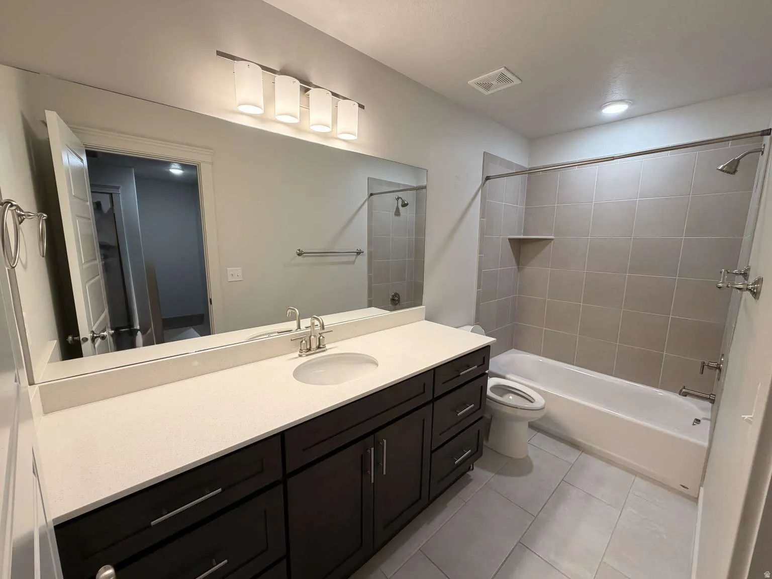 Spacious bathroom featuring a dark wood-finish vanity with a light-colored countertop, an undermount sink, and brushed nickel fixtures
