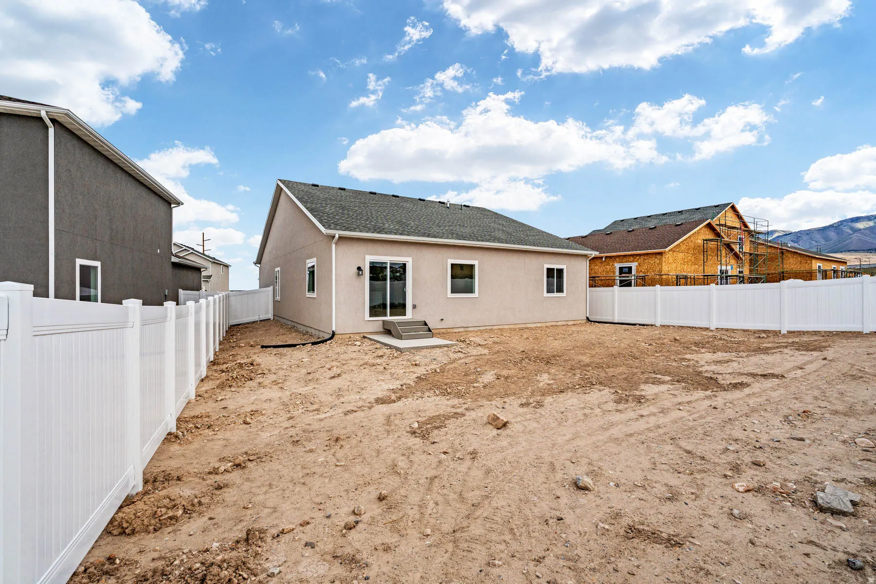 Rear exterior featuring a sliding glass door, white vinyl fencing, and a concrete patio pad
