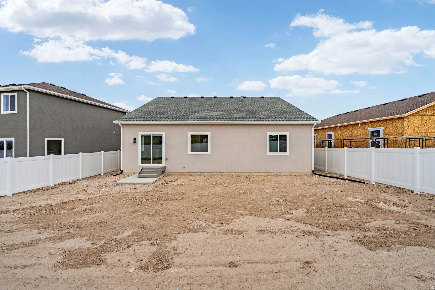 Rear exterior featuring a sliding glass door, two windows, and a concrete patio