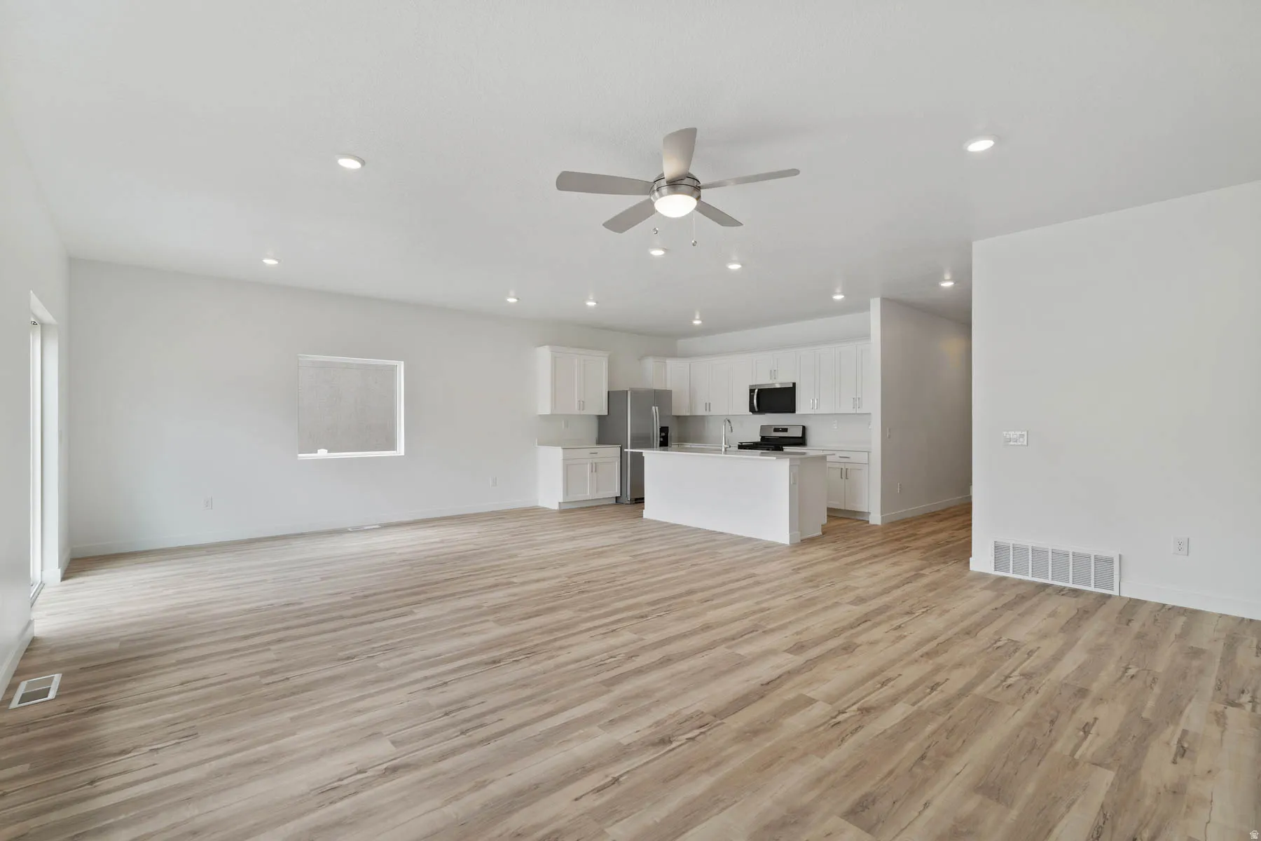 Open-concept living space featuring wood-finish flooring, recessed lighting, and a ceiling fan