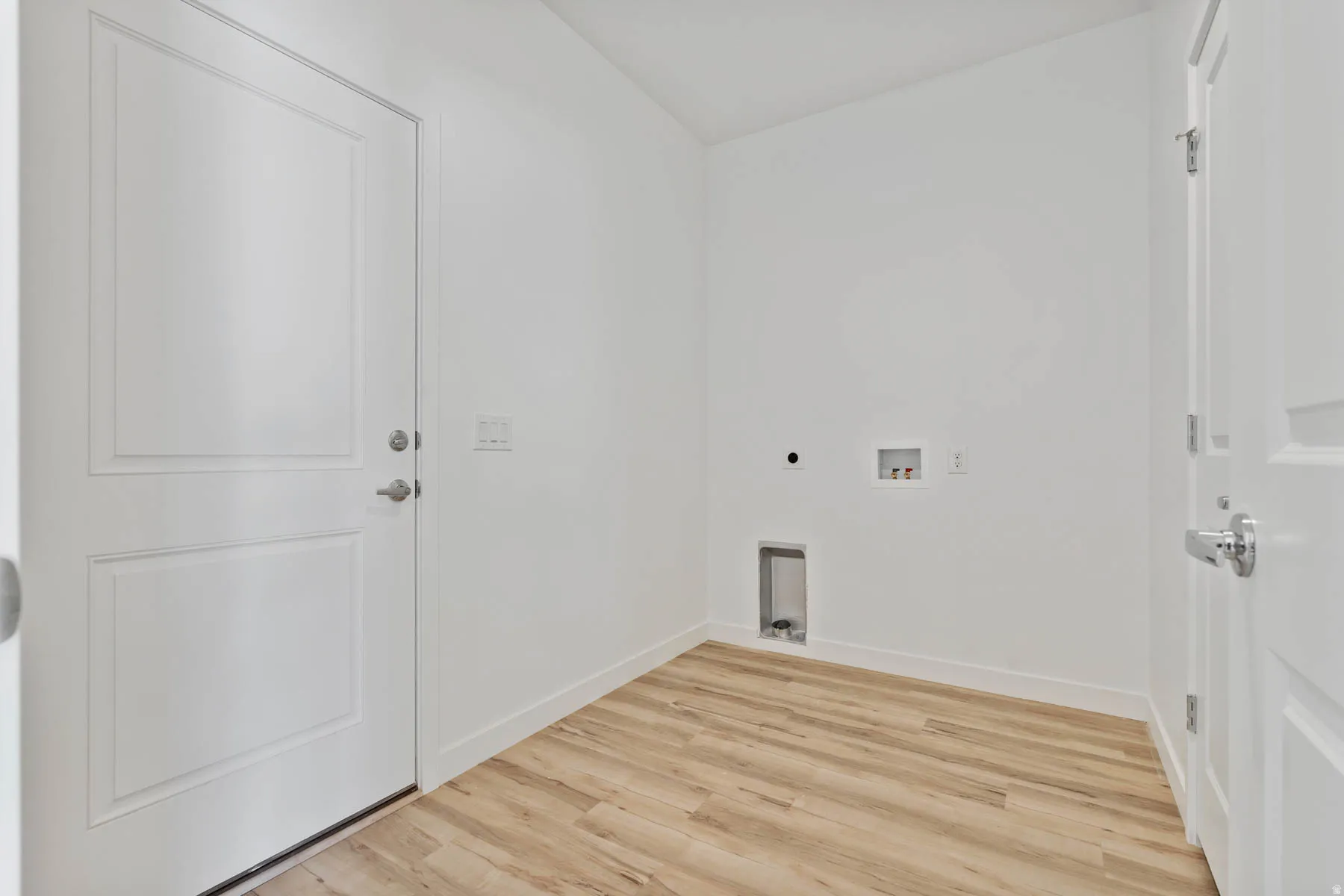 Utility space featuring wood-finish flooring, white walls, and two panel doors