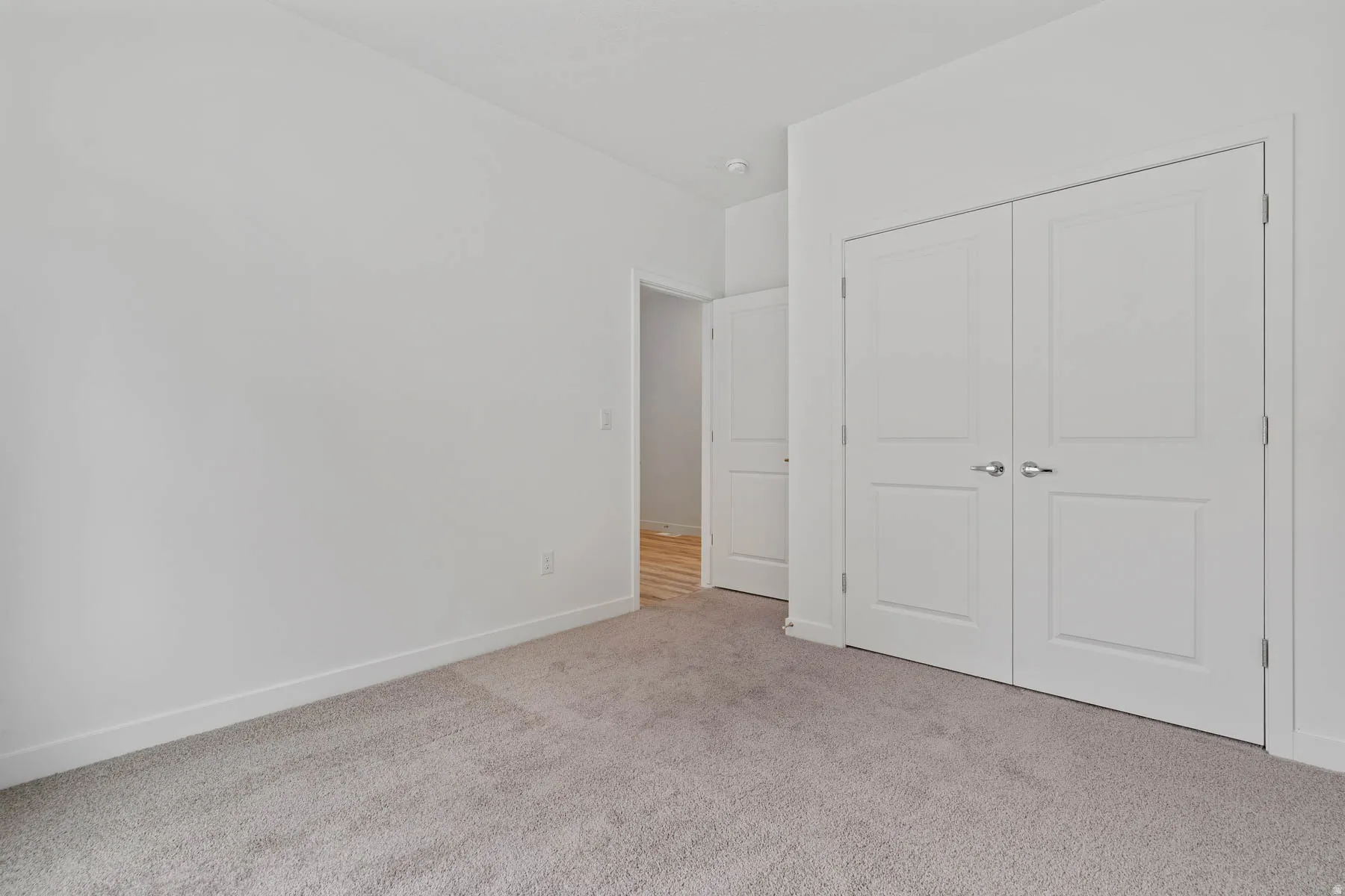 Light gray carpeted flooring, white walls, and white baseboards