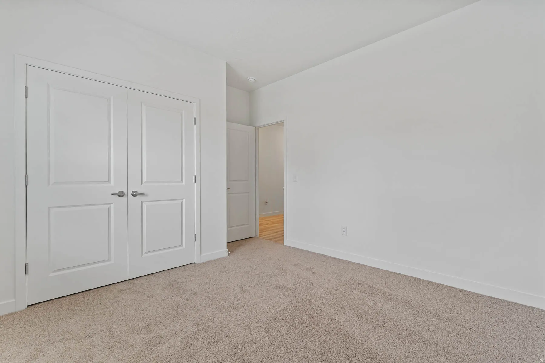 Neutral-toned carpeting extends throughout this interior space, complemented by crisp white walls and baseboards