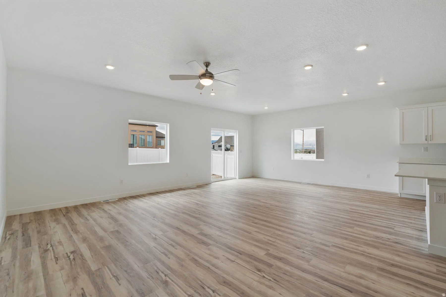 Open-concept living area featuring wood-finish flooring, recessed lighting, and a ceiling fan