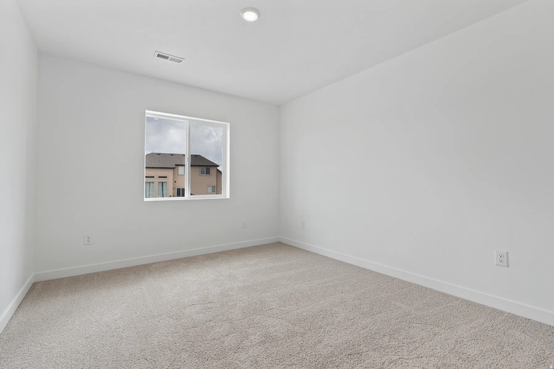 Neutral carpet flooring, white painted walls, recessed ceiling light, white trim, and a double-pane window