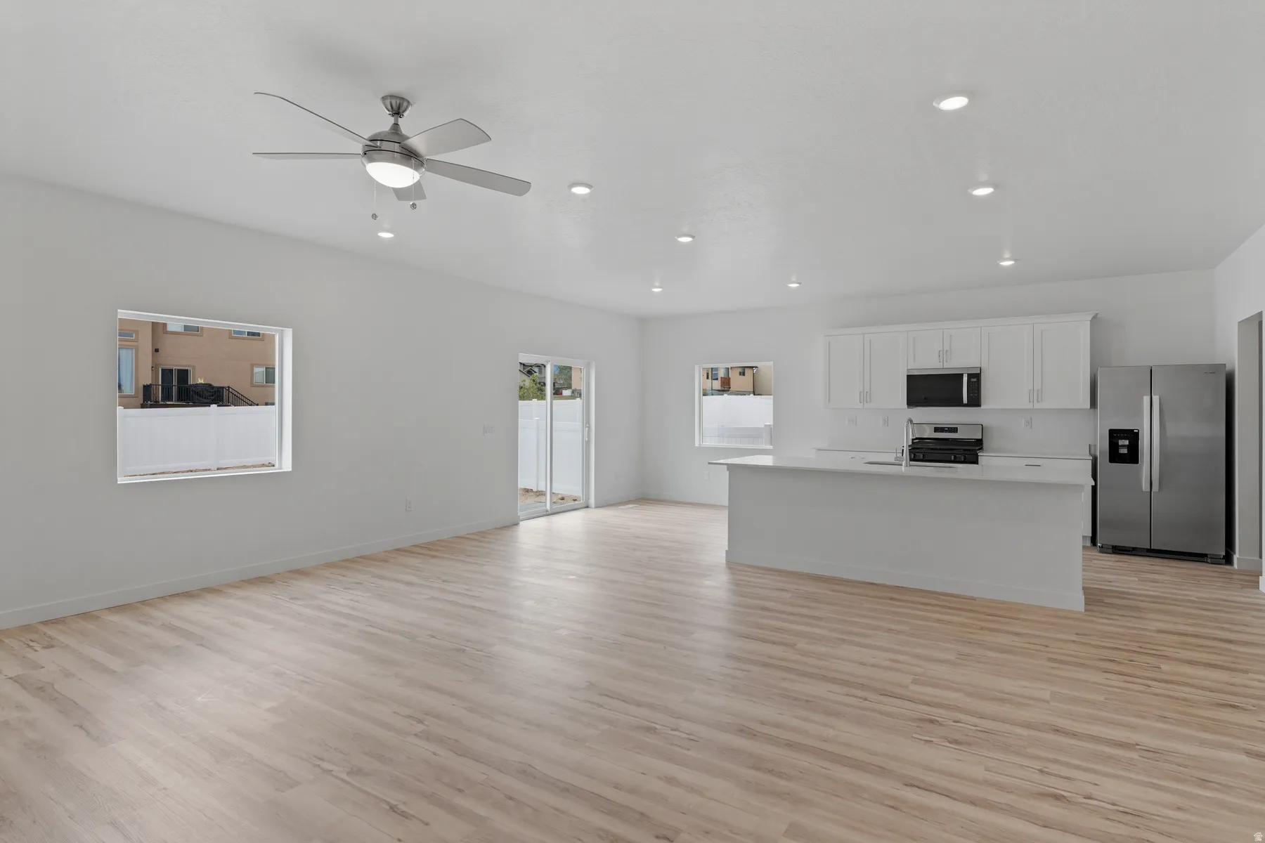 Open-concept living space featuring wood-finish flooring, recessed lighting, and a contemporary ceiling fan