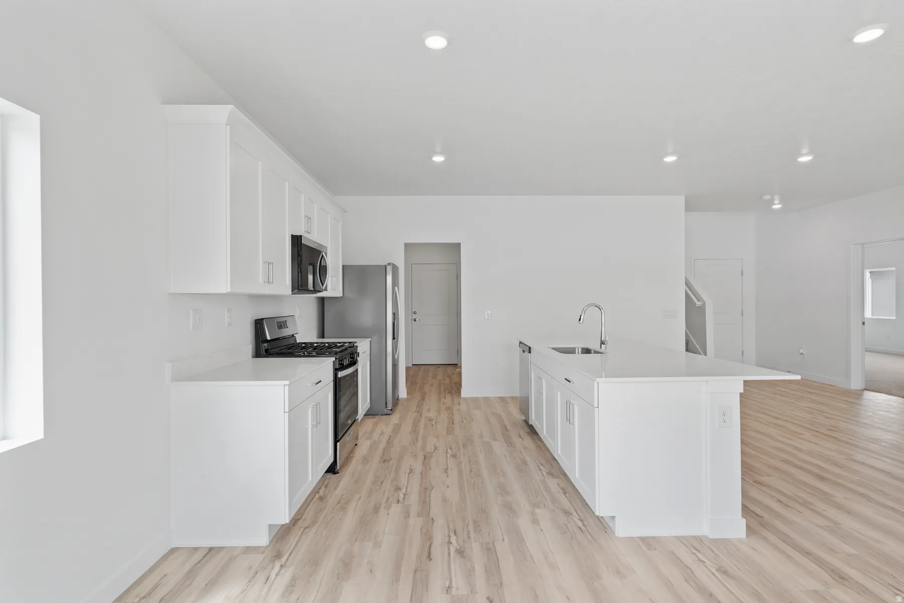Modern kitchen featuring white cabinetry, light-toned wood-finish flooring, and recessed lighting