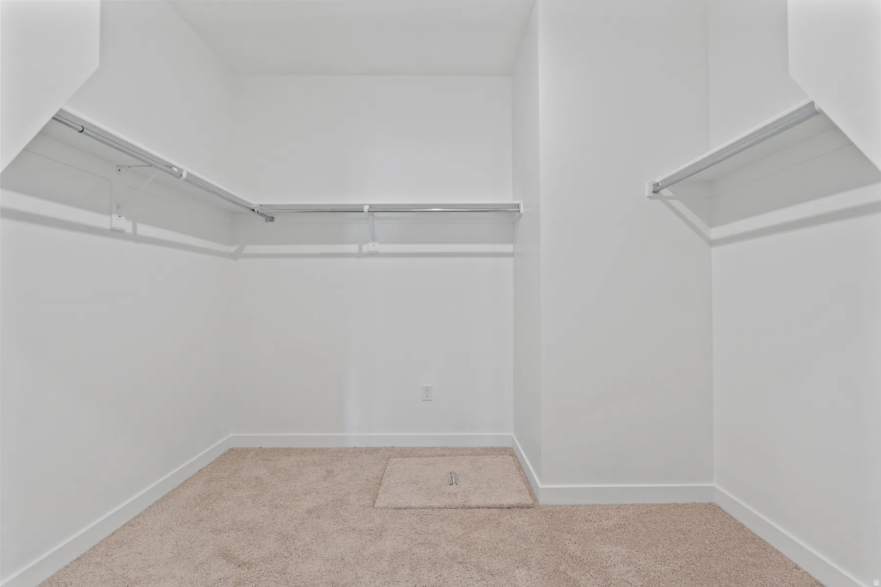 Spacious walk-in closet featuring light-colored carpet, white walls, white baseboards, and built-in metal shelving and hanging rods