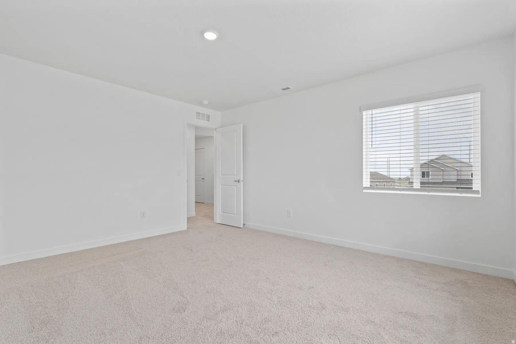 Neutral-toned wall-to-wall carpeting complements the white walls and trim