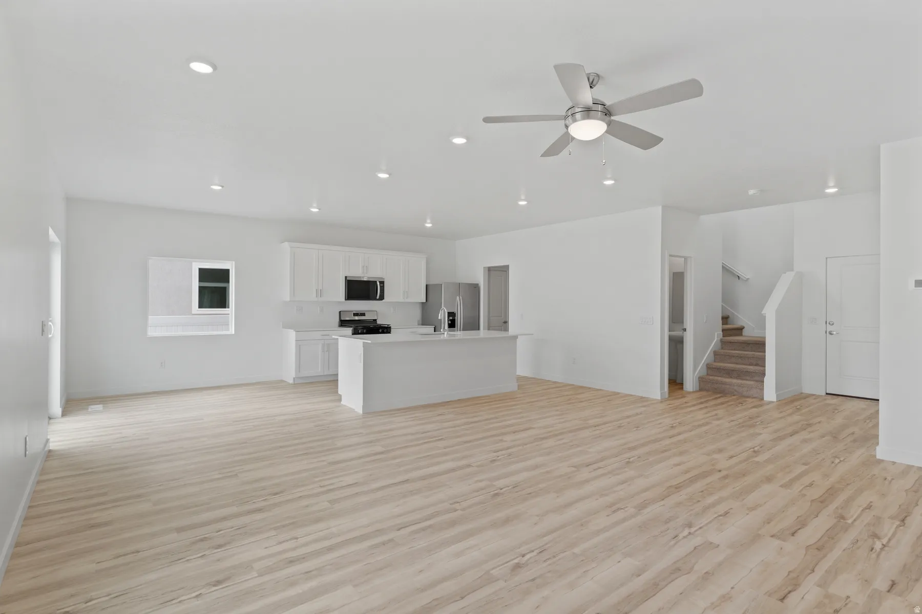 Open-concept living space featuring wood-finish flooring, recessed lighting, and a modern ceiling fan