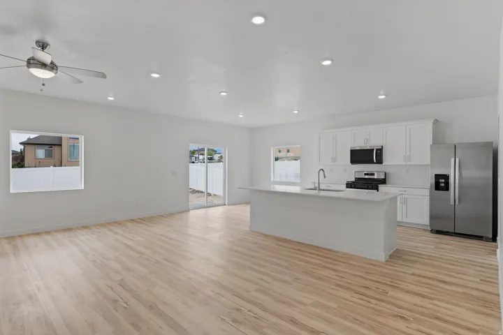 Open-concept living space featuring wood-finish flooring, recessed lighting, and a ceiling fan with integrated illumination