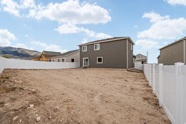 Expansive backyard lot featuring a white vinyl privacy fence and a mountain backdrop