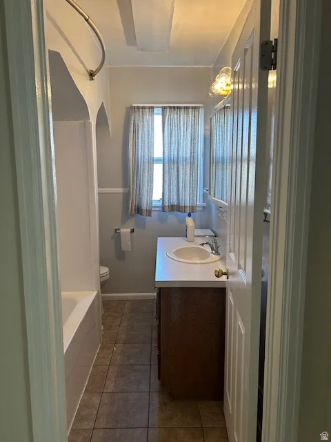 Full bath featuring vanity, dark tile patterned floors, and bathing tub / shower combination