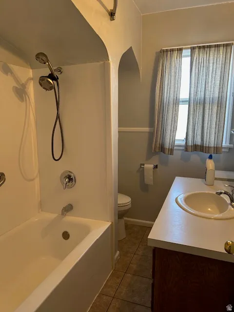 Full bath with vanity, dark tile patterned flooring, and shower / bath combination