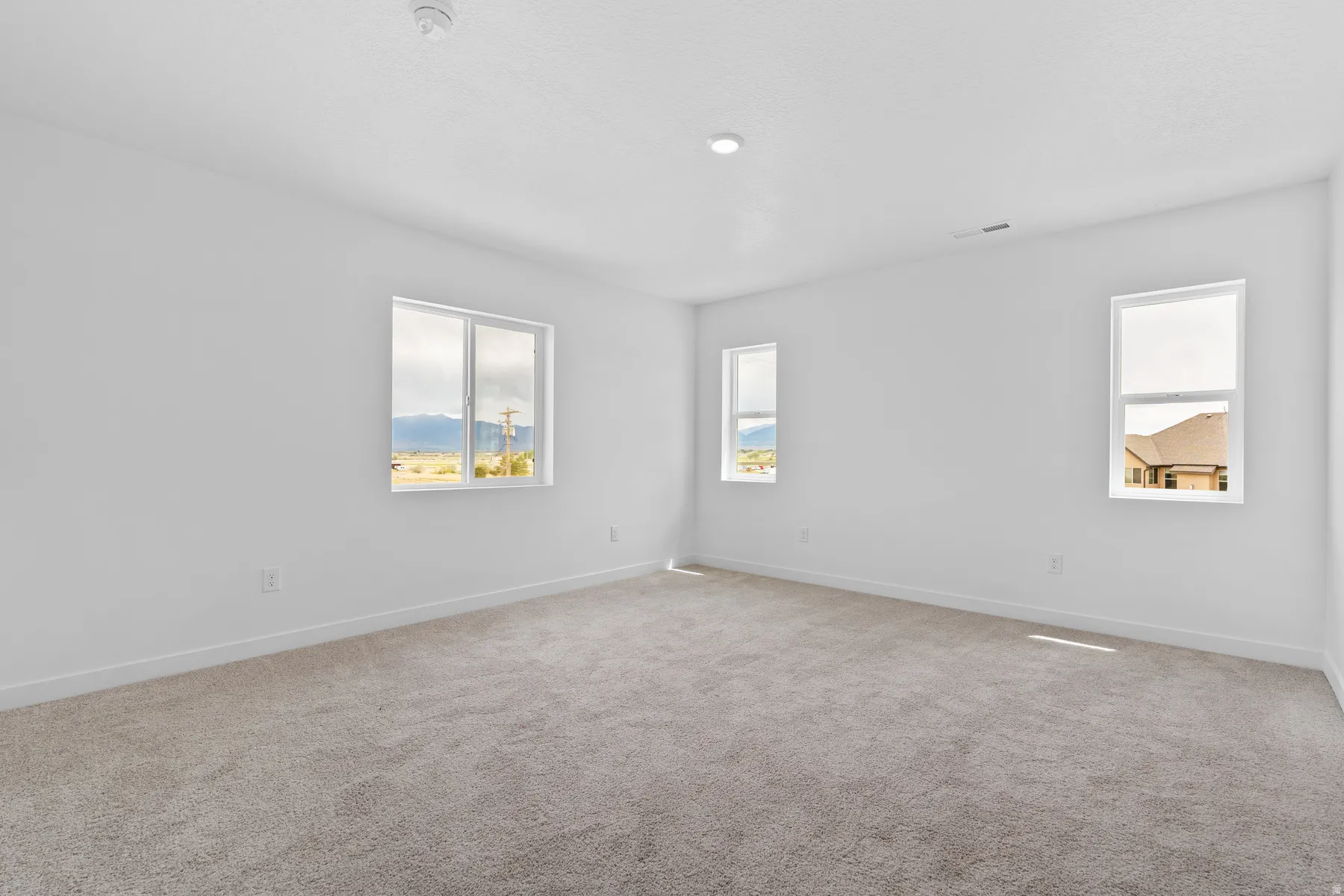 Spacious room featuring neutral carpeting and white walls