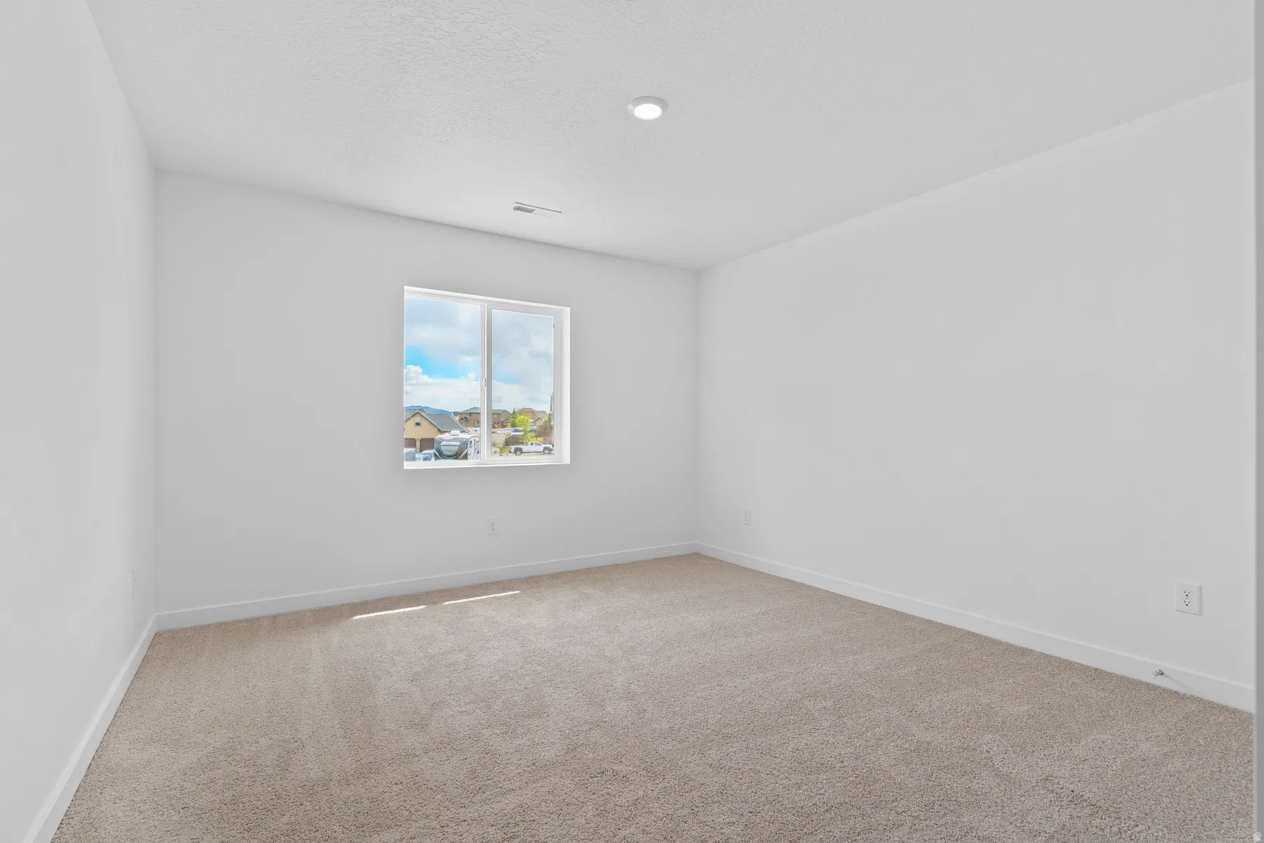 Spacious room featuring neutral carpeting, white walls, and a recessed ceiling light
