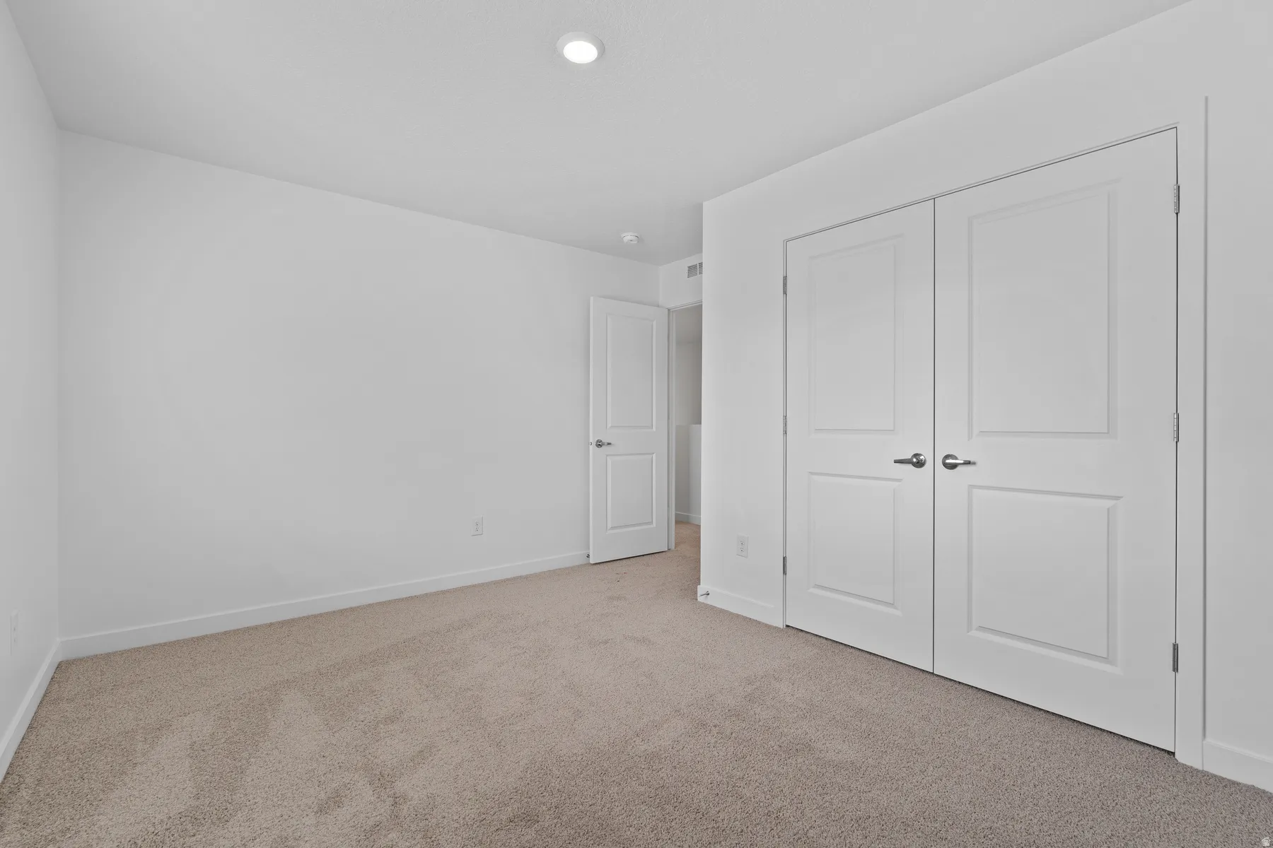 Neutral tone-on-tone carpet flooring complements the crisp white walls