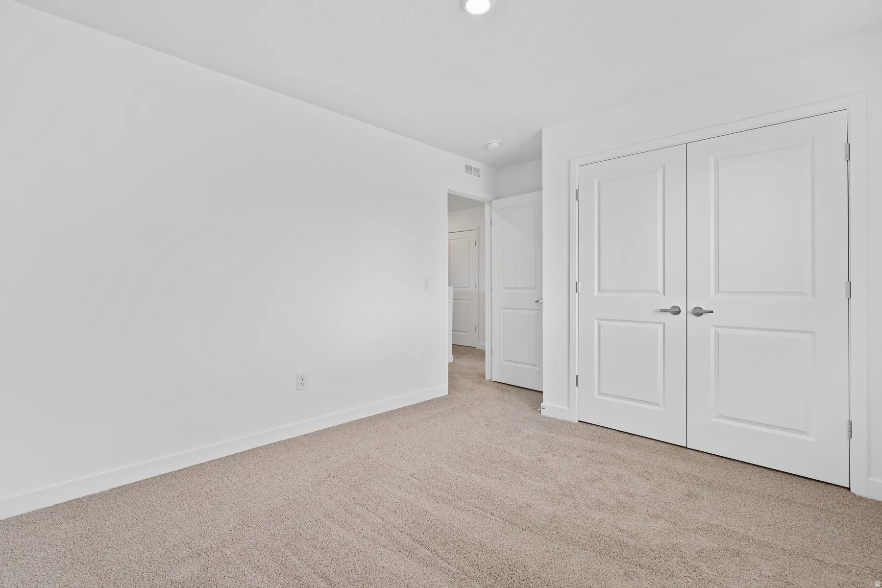 Neutral-toned carpeting paired with white baseboards and walls