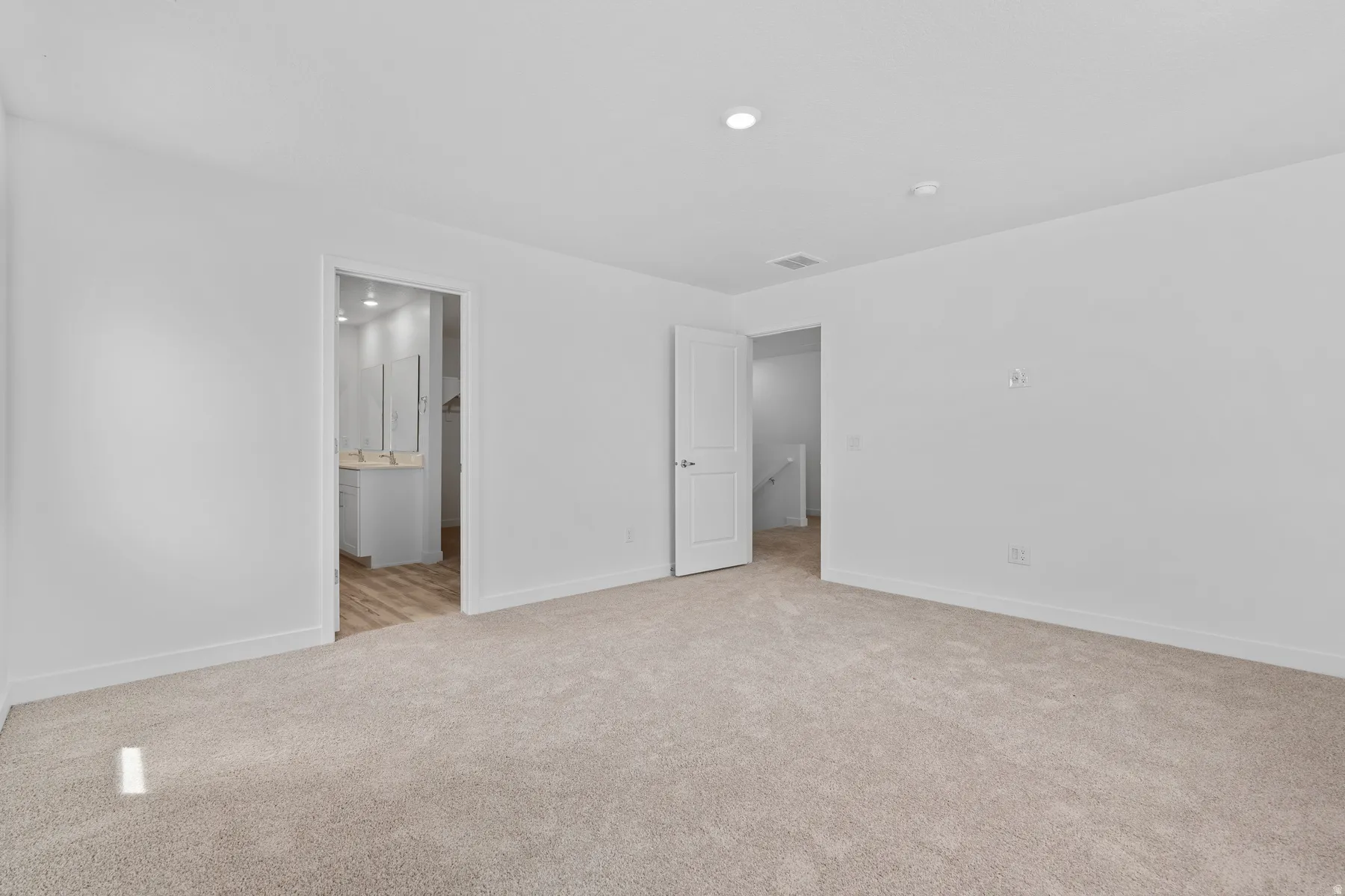 Carpeted room with recessed lighting and crisp white walls