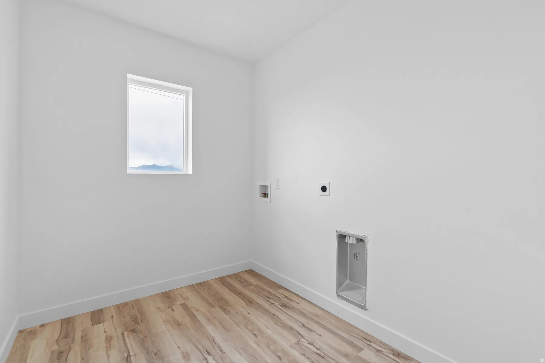 Utility room featuring wood-finish flooring, a single pane window, and white trim