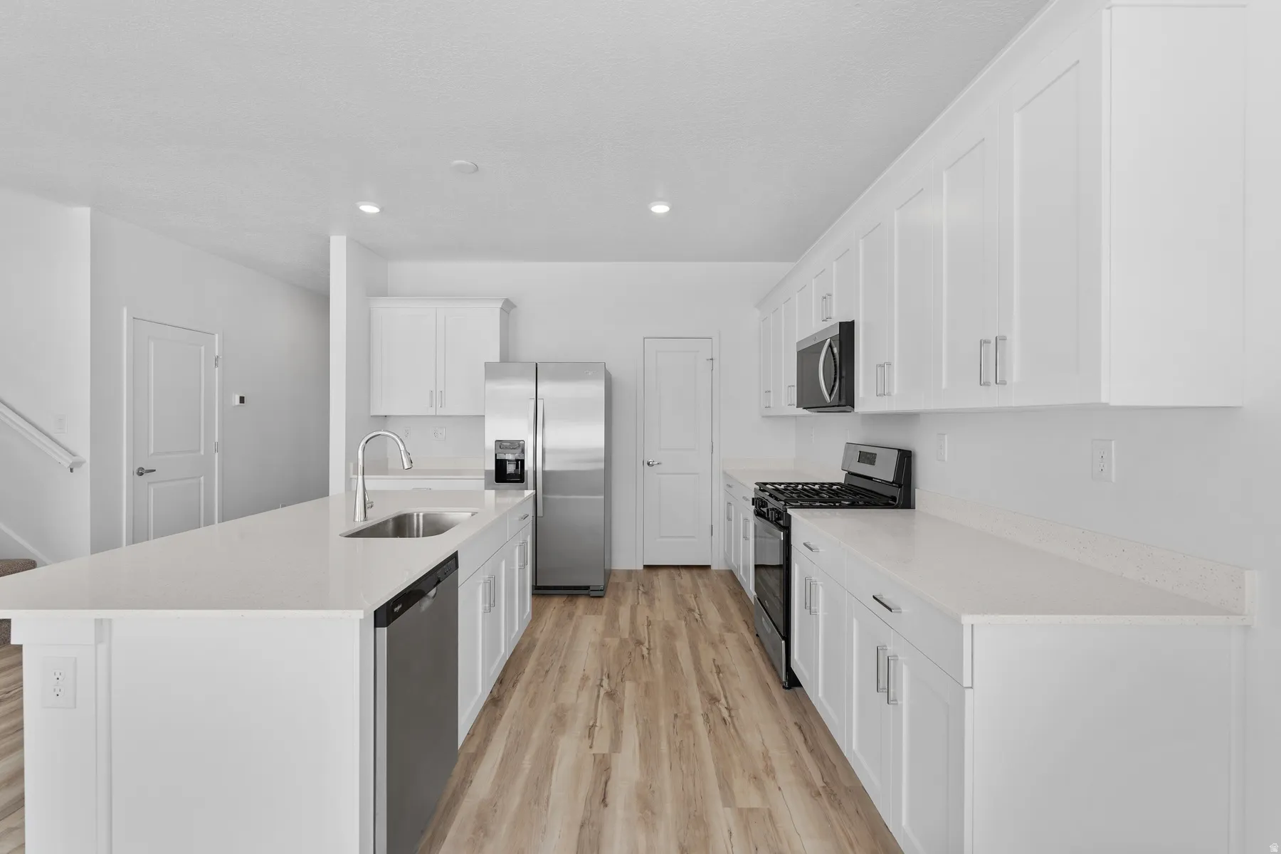 Modern kitchen featuring white cabinetry, light-toned wood-finish flooring, and white countertops