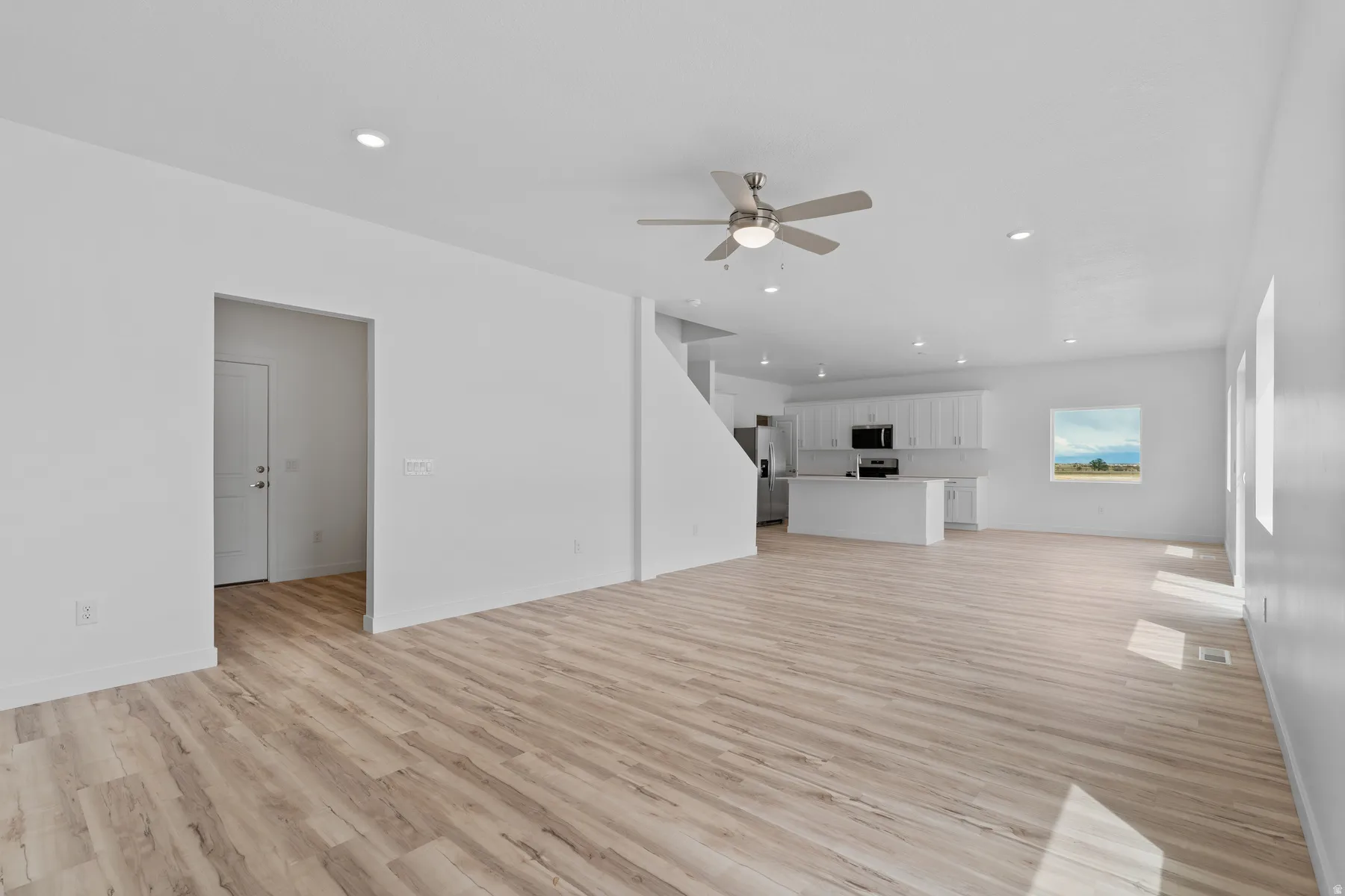 Open-concept living area featuring wood-finish flooring, recessed lighting, and a ceiling fan