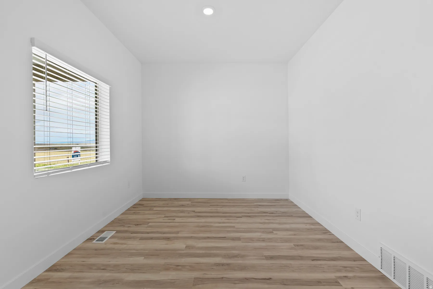Room featuring wood-finish flooring, white baseboards, and bright white walls