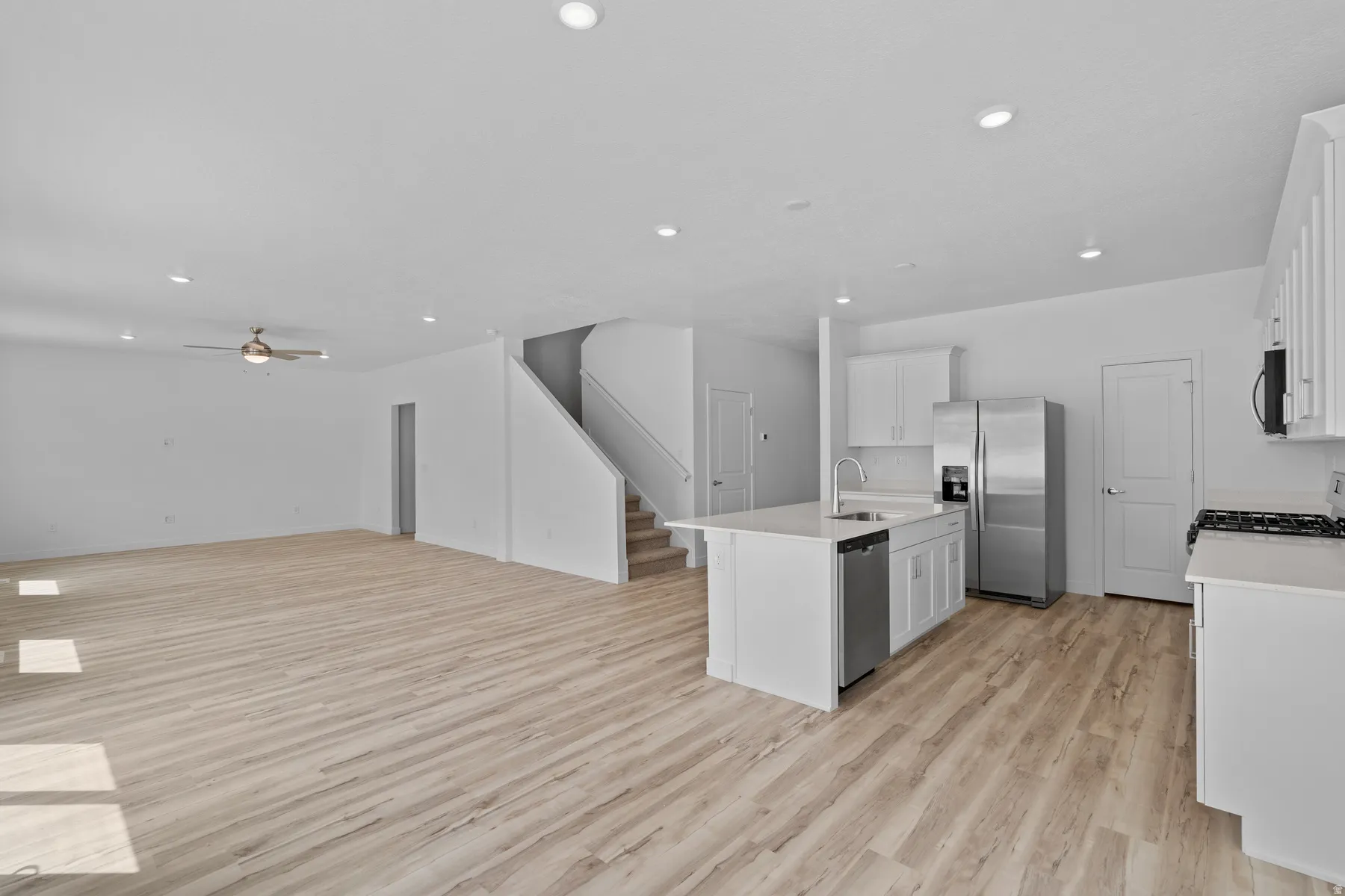 Open-concept living space featuring wood-finish flooring, recessed lighting, and a modern kitchen