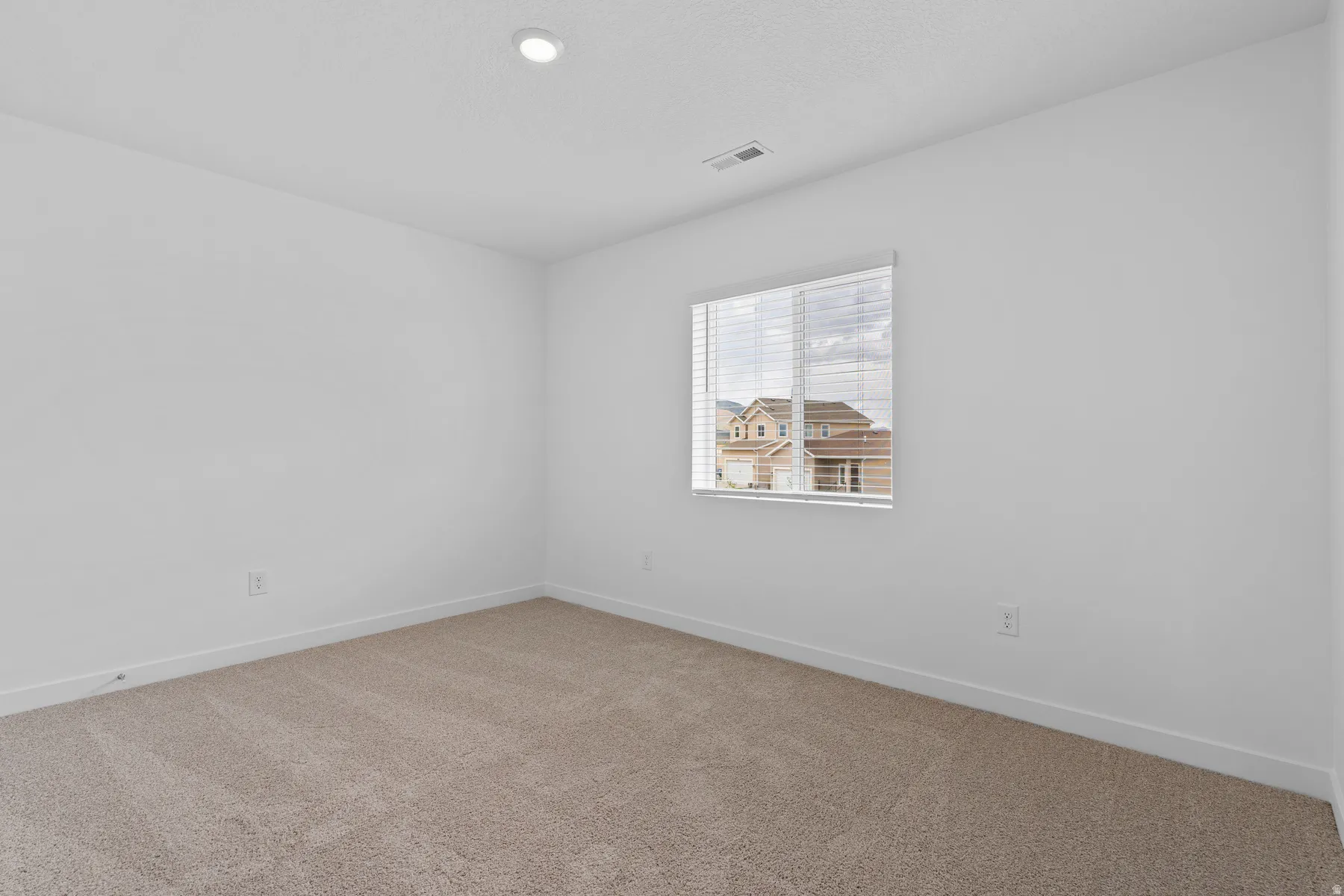Carpeted room featuring a single window with blinds, recessed lighting, white walls, and white baseboards