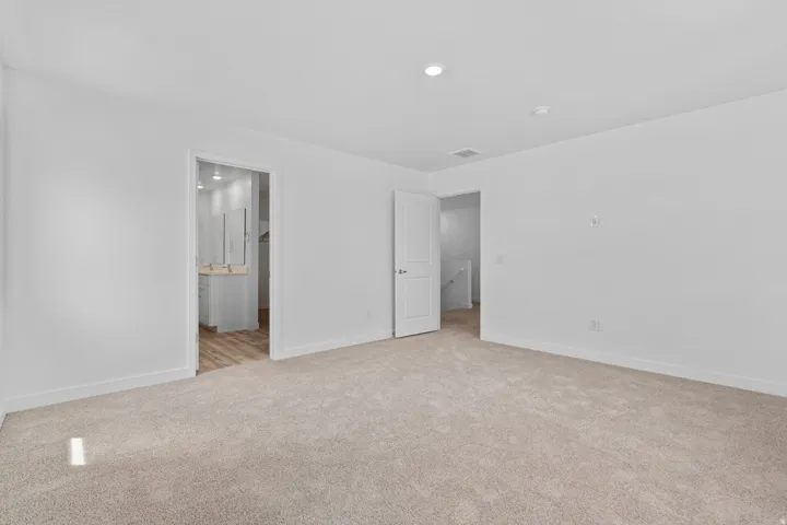 Carpeted room with recessed lighting and crisp white walls