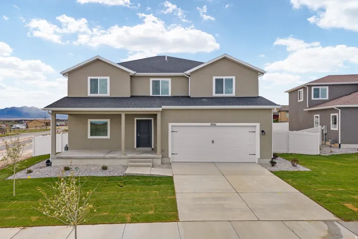 Contemporary two-story stucco residence featuring a covered front porch, an attached two-car garage, and a concrete driveway