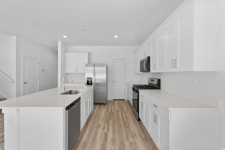 Modern kitchen featuring white cabinetry, light-toned wood-finish flooring, and white countertops