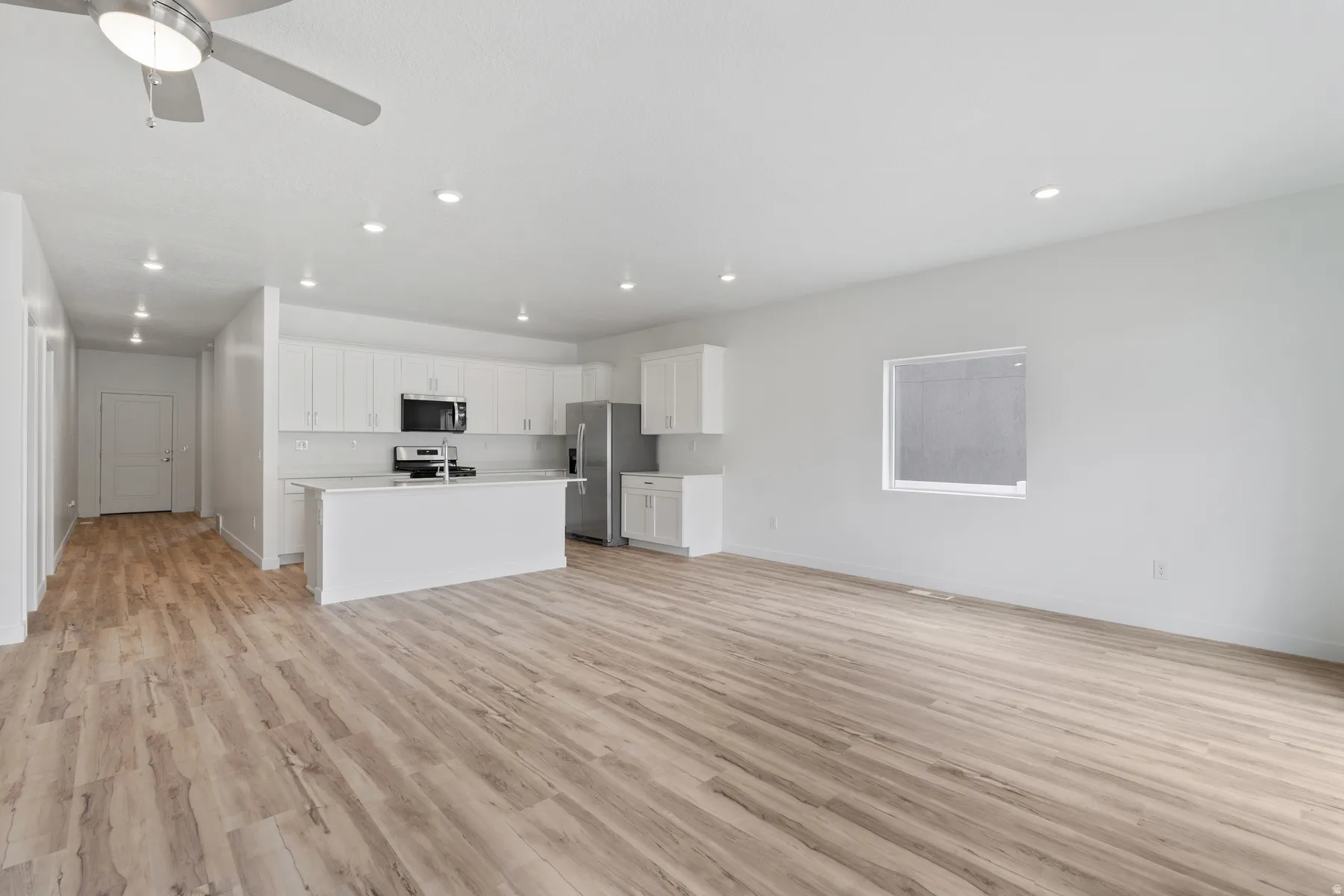 Open concept living area featuring wood-finish flooring, recessed lighting, and a ceiling fan