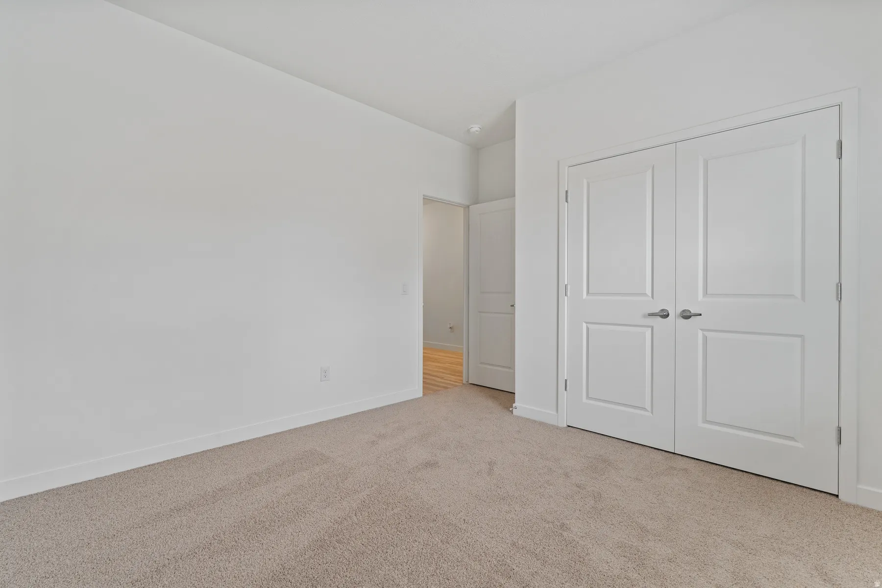 Neutral tone wall paint with white trim, light-colored carpet flooring, and white paneled double doors