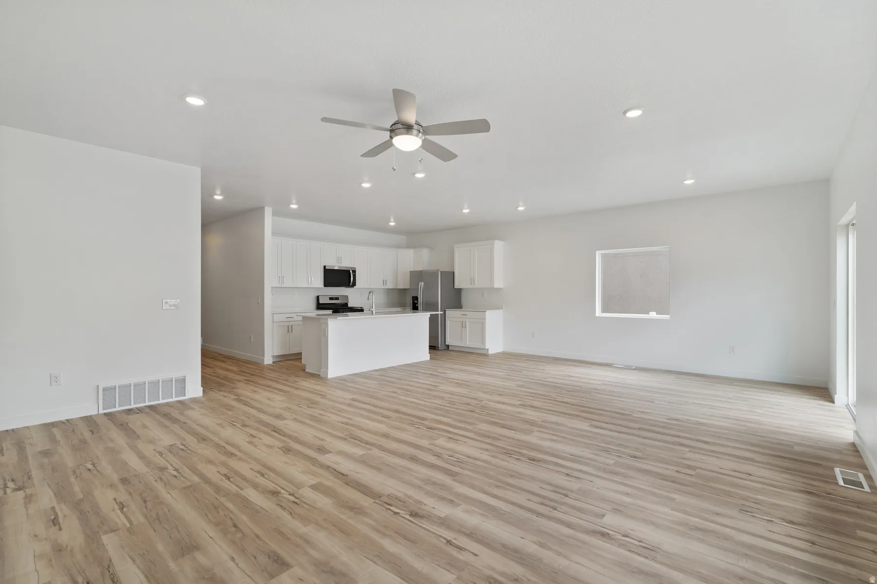 Open-concept living space featuring wood-finish flooring, recessed lighting, and a ceiling fan