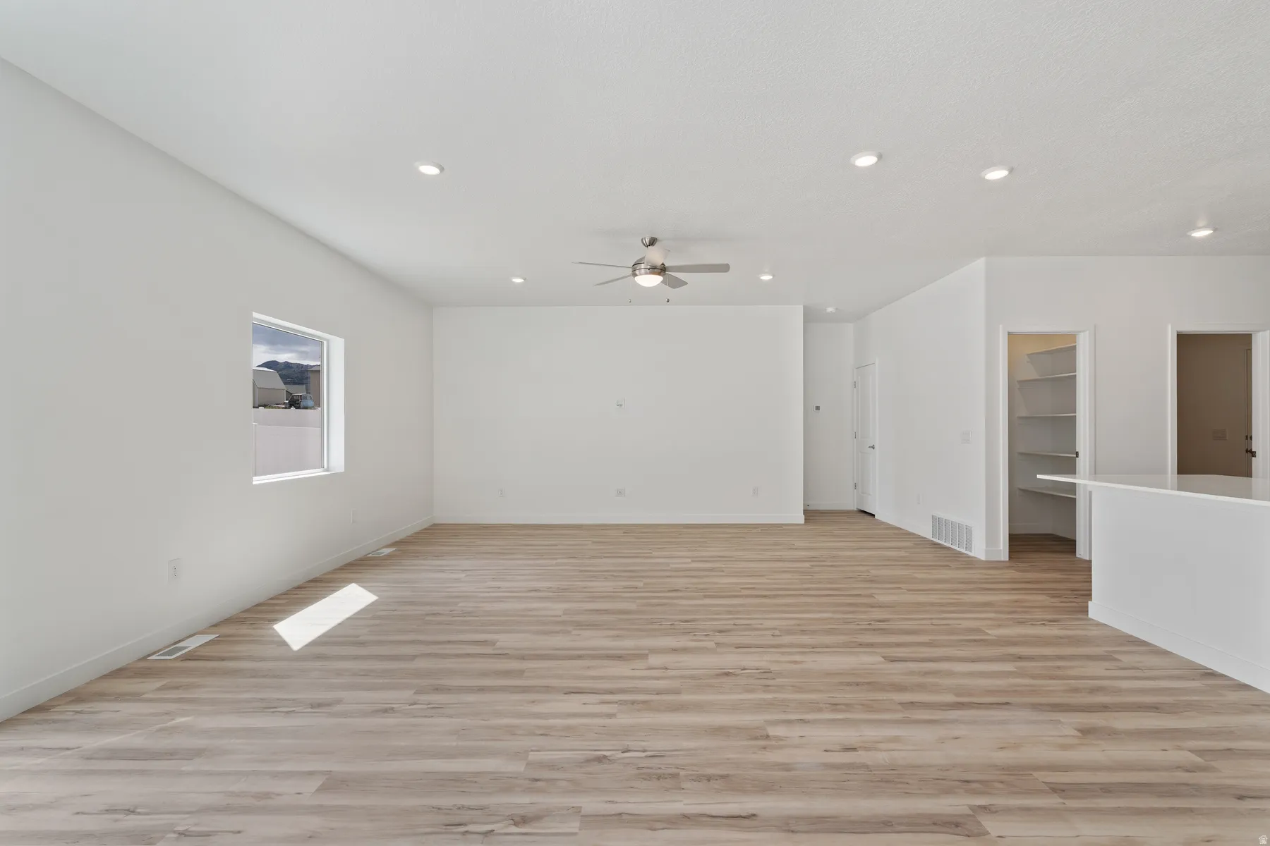 Spacious interior featuring light wood-finish flooring, recessed lighting, and a ceiling fan