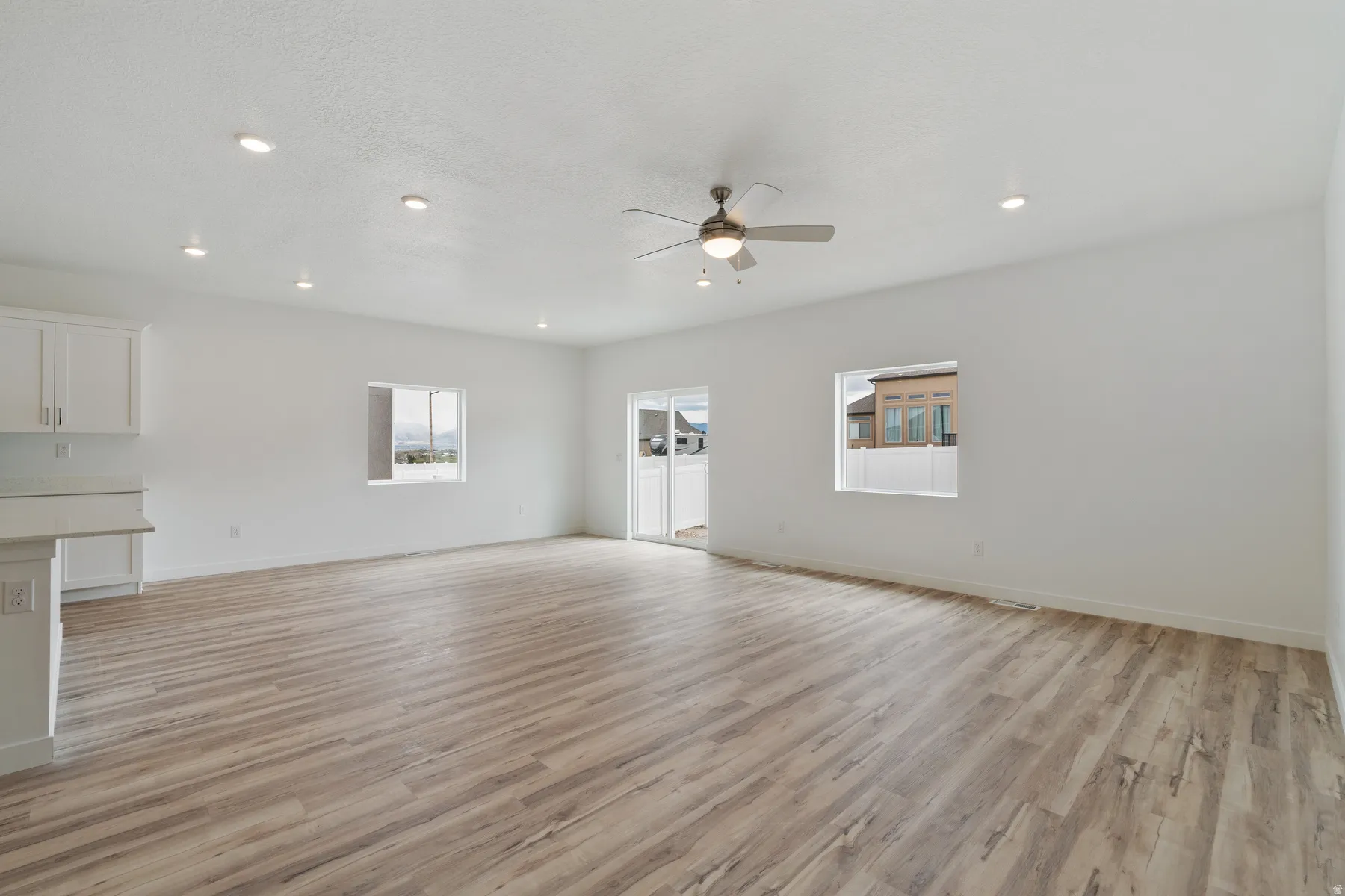Spacious open-concept room featuring wood-finish flooring, recessed lighting, and a ceiling fan