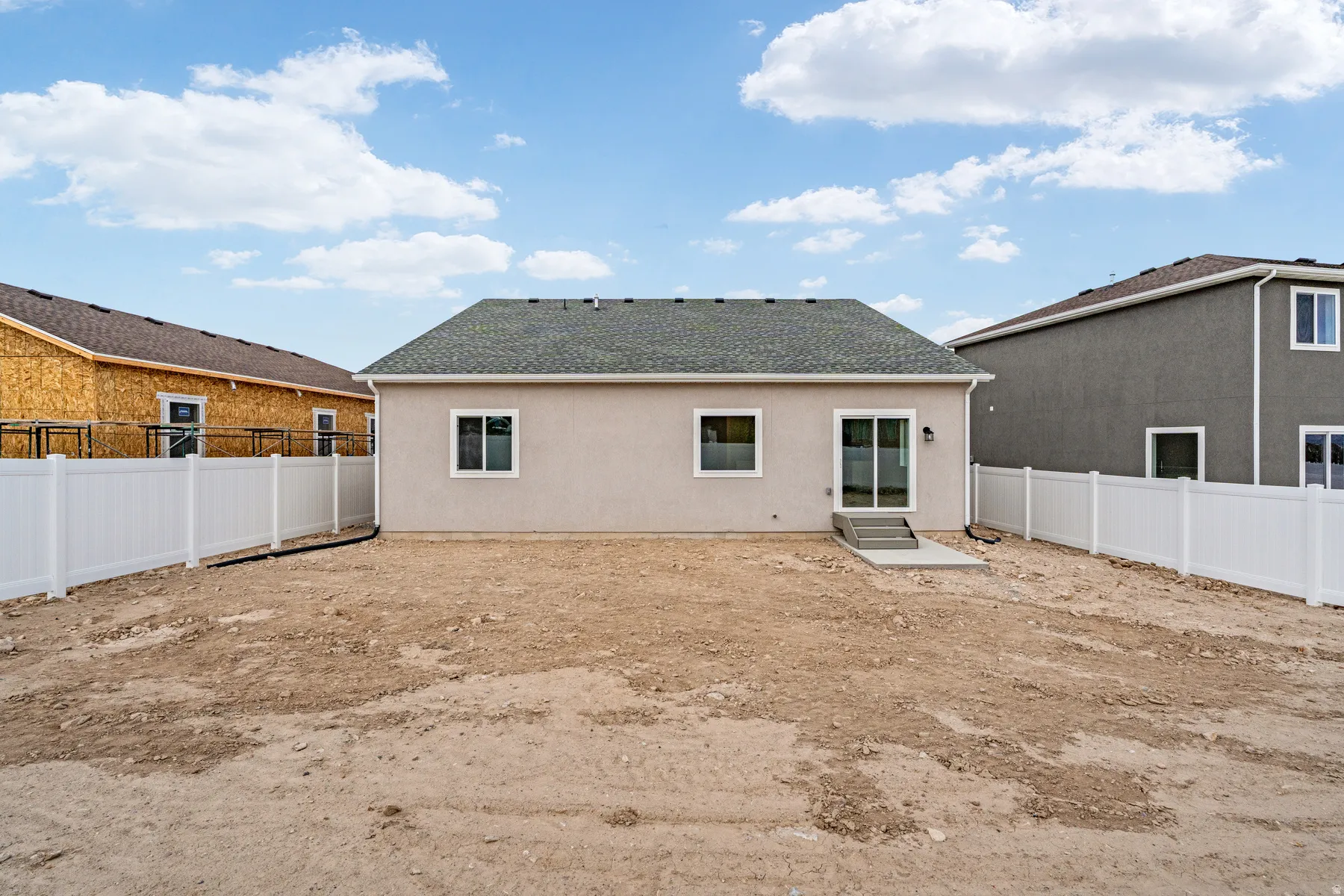 Rear exterior featuring a stucco finish, dual-pane windows, and a sliding glass patio door