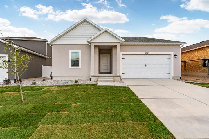 Contemporary stucco exterior with a white garage door, concrete driveway, and a partially sodded front yard