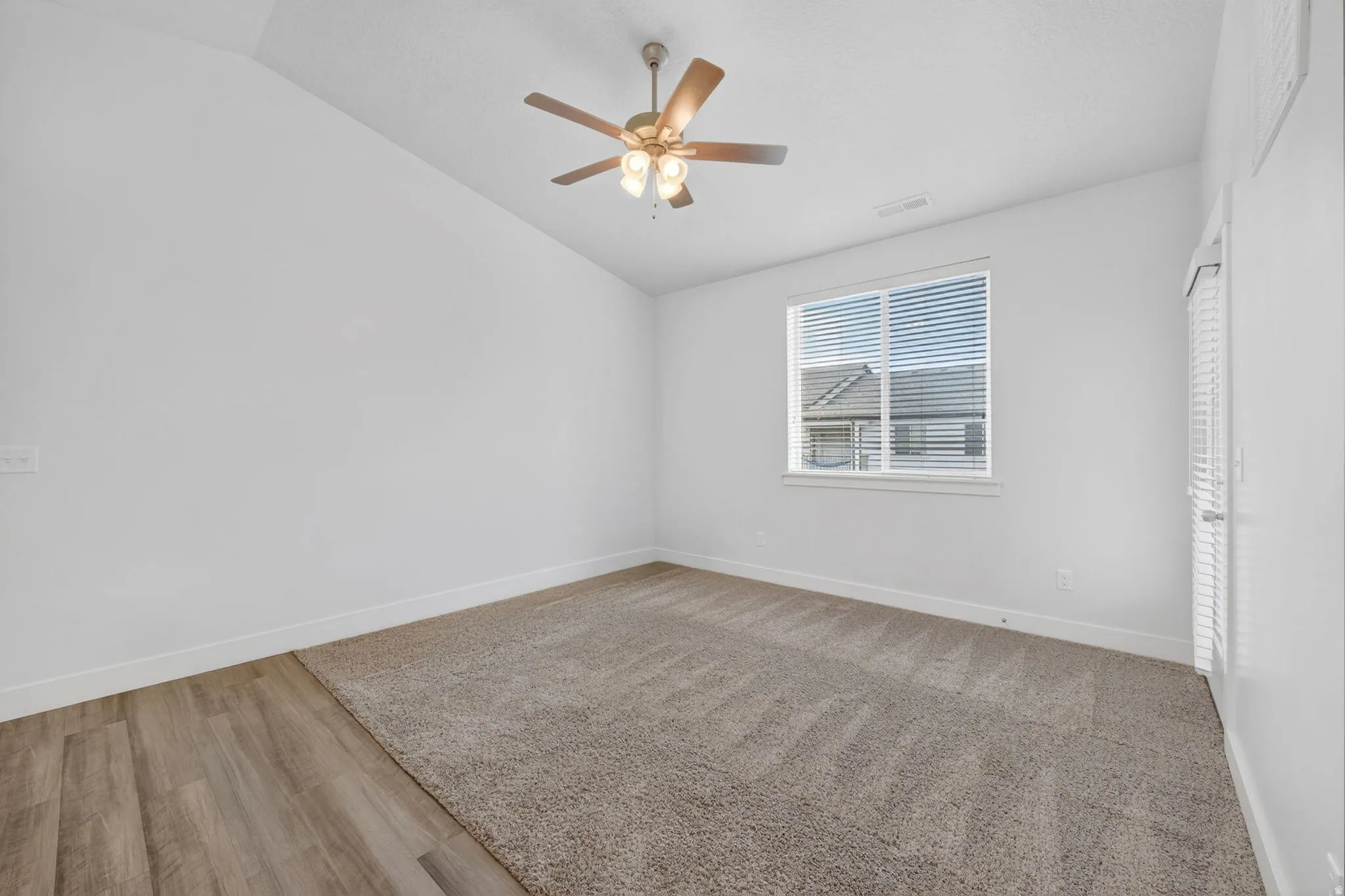 Empty room featuring lofted ceiling, a ceiling fan, and light wood finished floors
