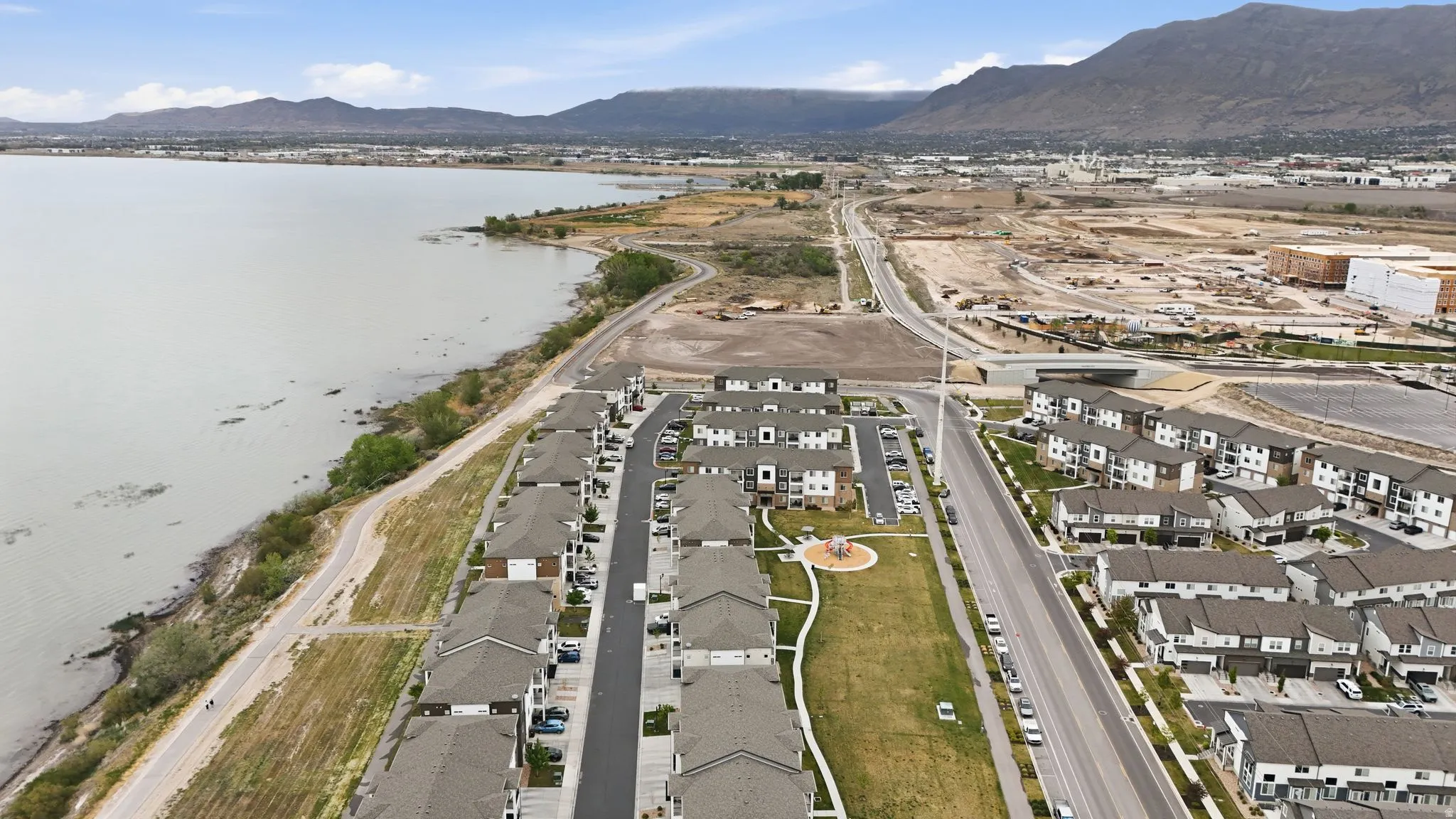 Aerial view of property and surrounding area featuring nearby suburban area and a water and mountain view