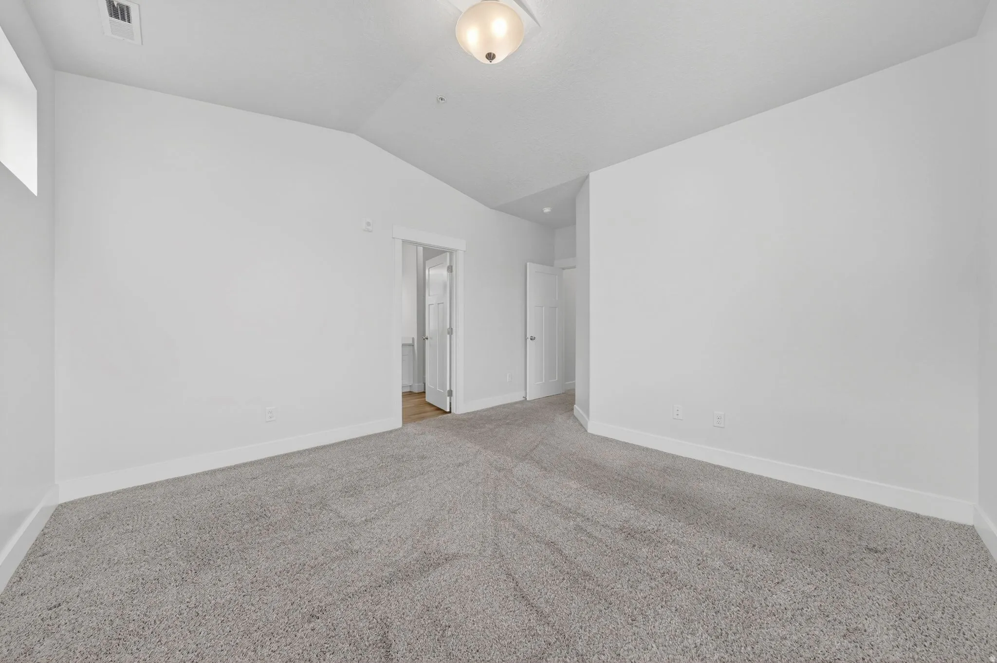 Unfurnished room featuring vaulted ceiling and light colored carpet