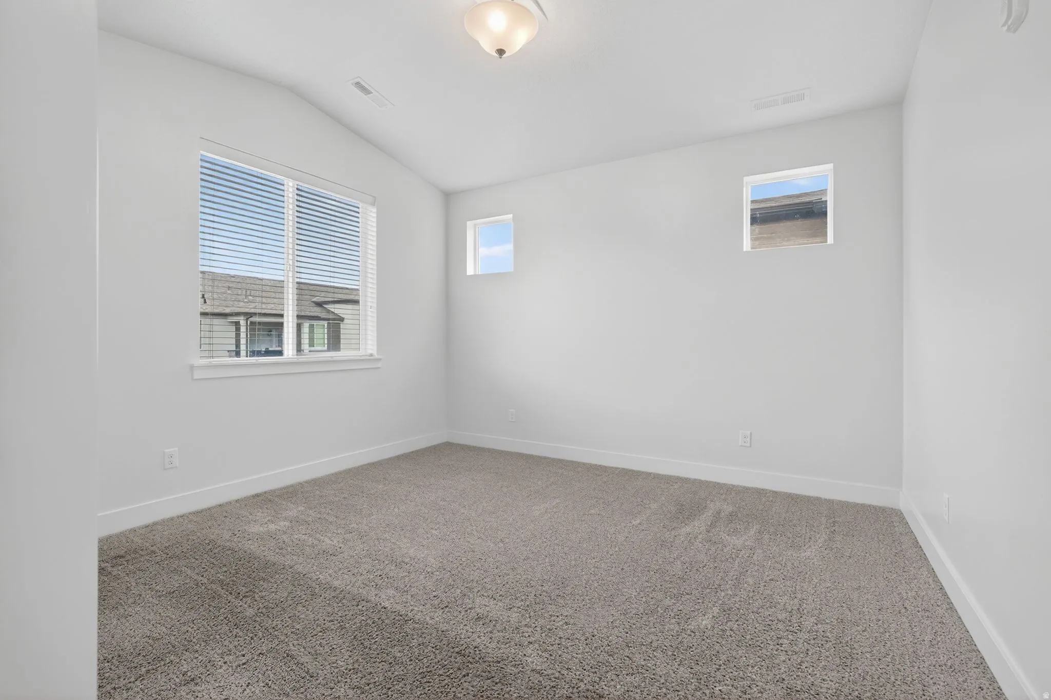 Spare room with carpet flooring, vaulted ceiling, and plenty of natural light